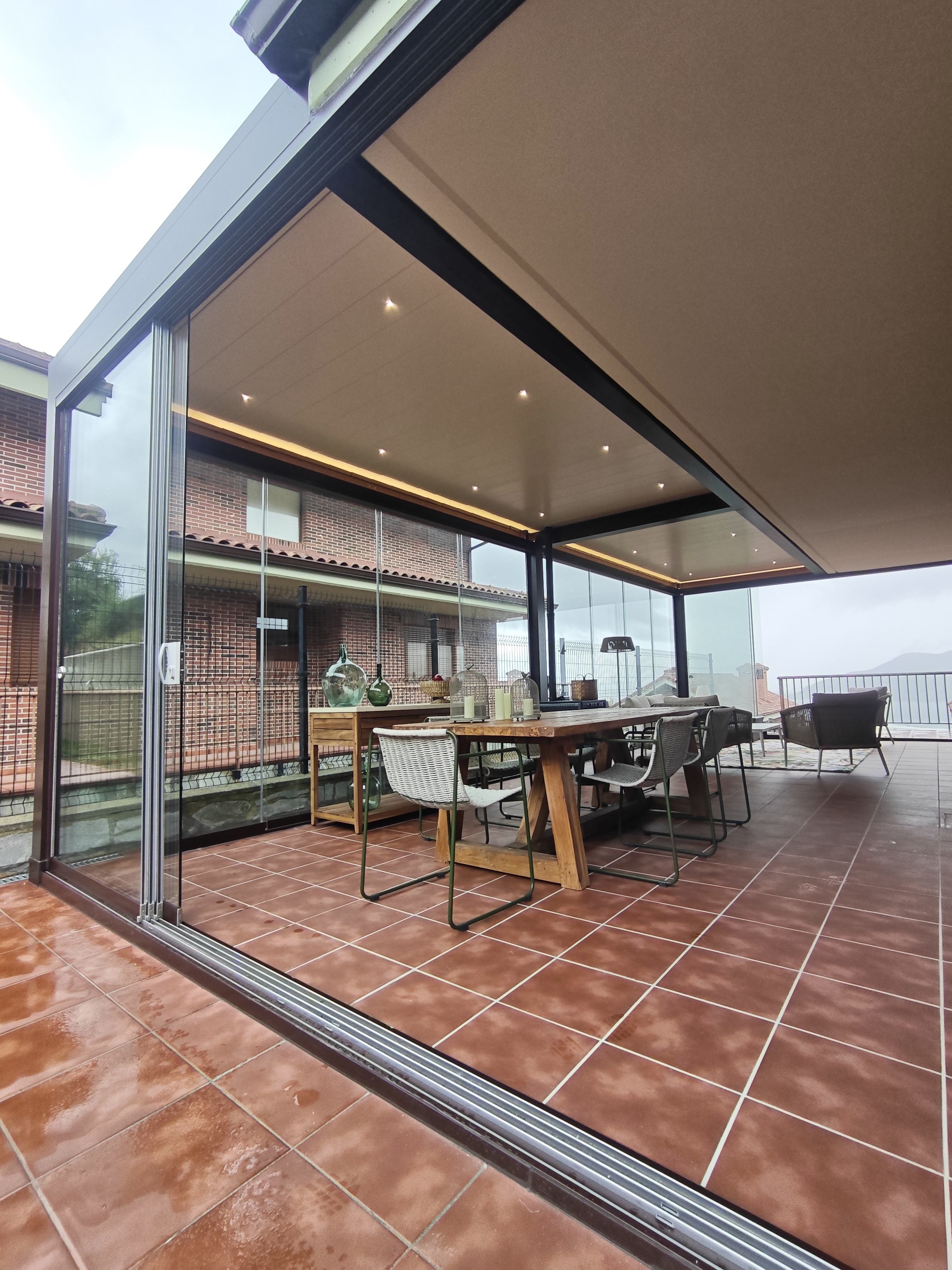Pérgola bioclimática de aluminio gris con lamas orientables sobre una terraza